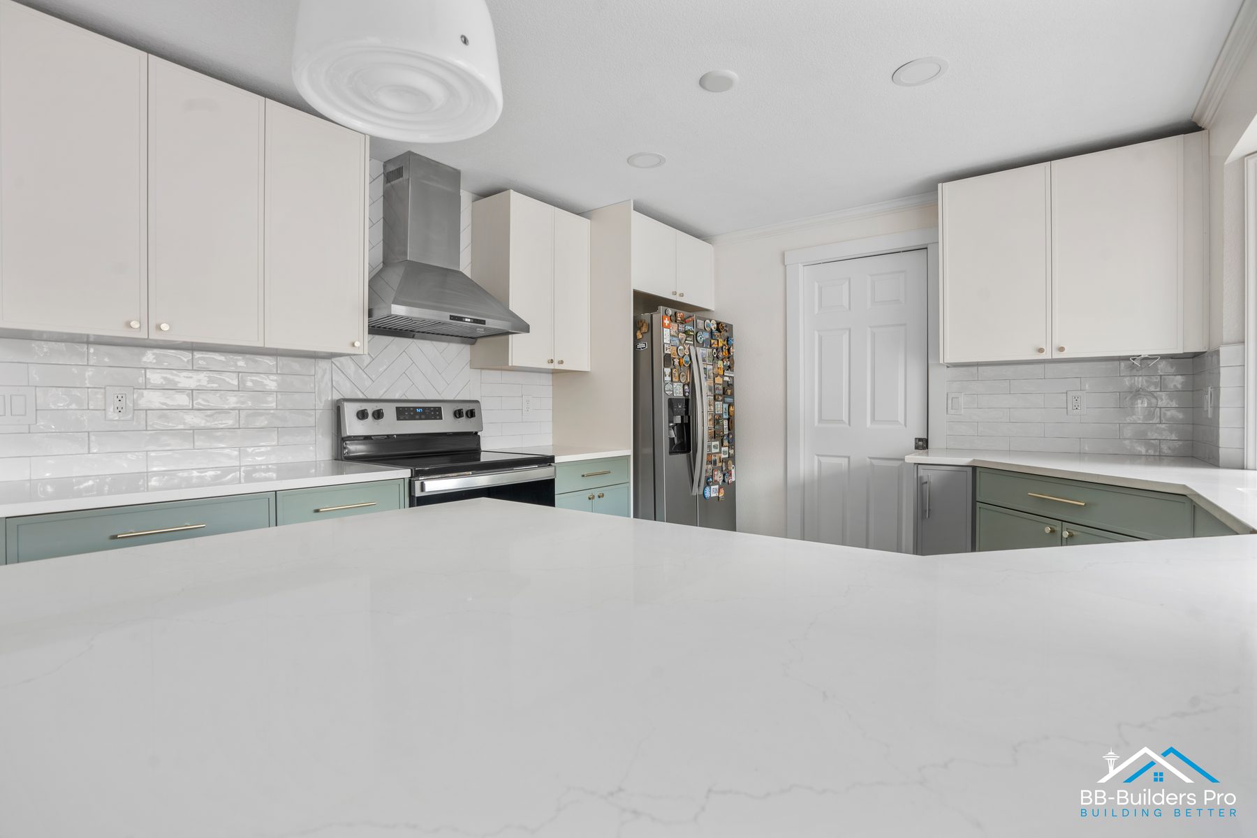 A finished kitchen remodel by BB-Builders Pro — white quartz island, sage cabinets, herringbone backsplash